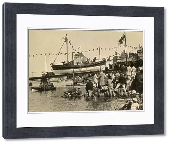Swanage motor lifeboat Thomas Markby being launched down the slipway, crowds of people gathered on the shore. Black and white photo taken in 1928