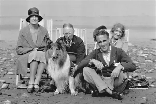 Four people on beach with collie dog