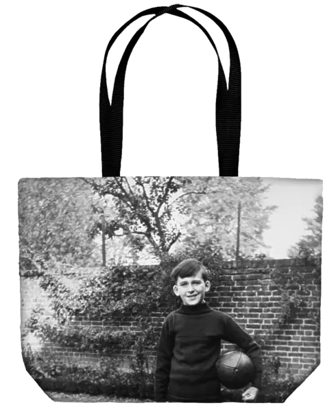Boy standing in garden with rugby ball, Eltham, London