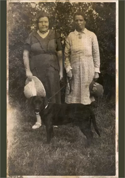 Two women with a dog in a garden