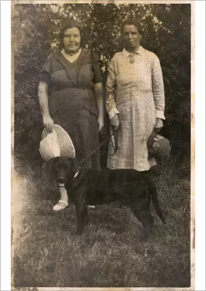 Two women with a dog in a garden
