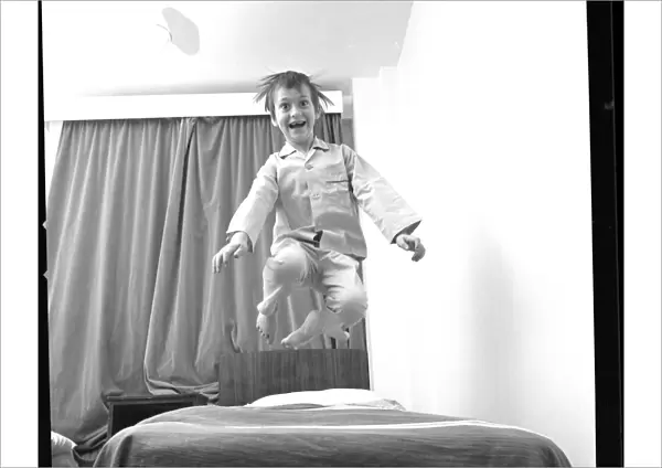 Boy bouncing up and down on a bed