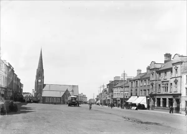 Lurgan - a street scene with motor bus and people and shop fronts and church