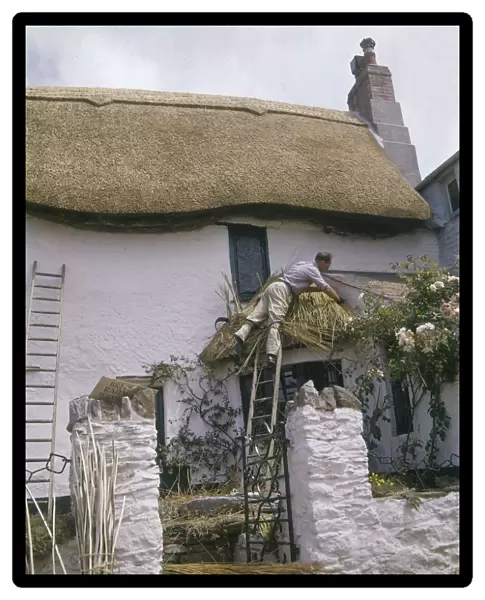Man at work thatching a cottage roof, West Country