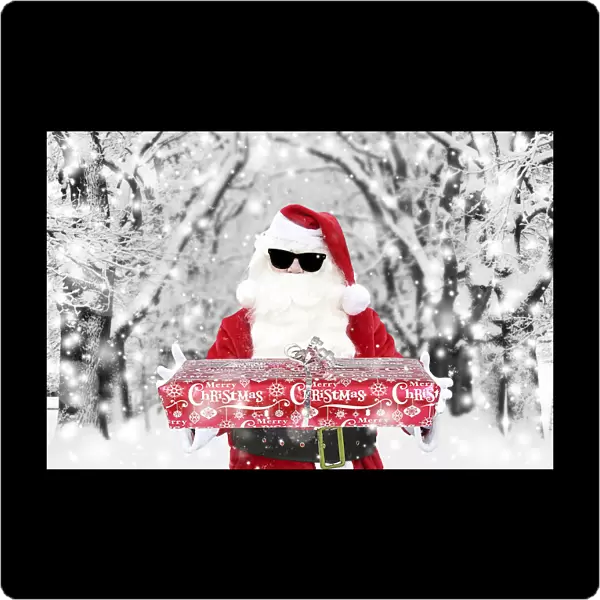 Father Christmas  /  Santa Claus wearing sunglasses holding Christmas present in winter snow