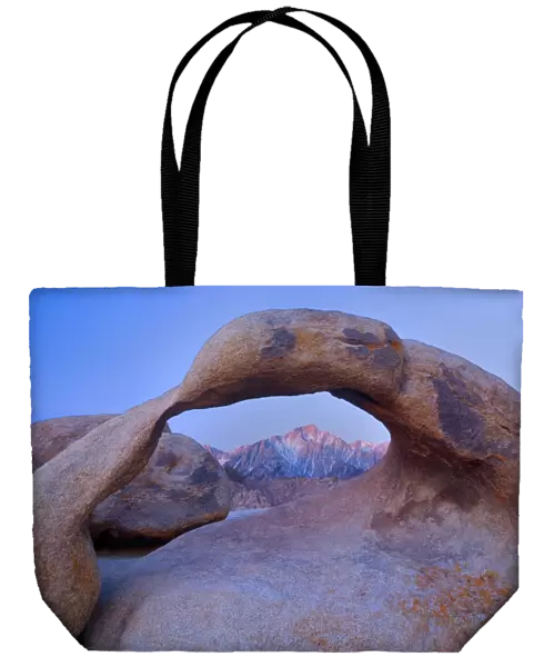 Mobius Arch - alpenglow on Lone Pine, one of the snow-capped mountains of the Sierra Nevada, seen through ock arch of red granite. At sunrise - Alabama Hills Recreation Area, California, USA