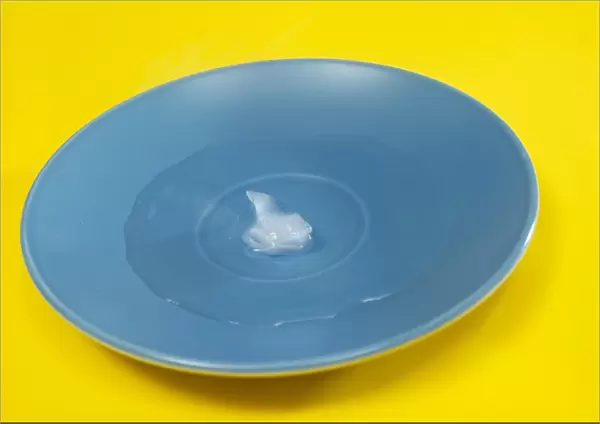 Ice cube nearly melted on a plate. Image 2 of 2