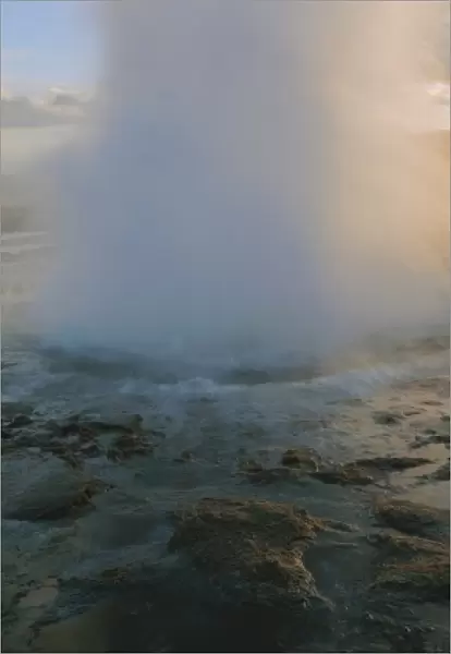 Geyser erupting. A geyser is a deep natural well in a geothermal rock fissure