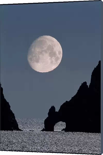 Gibbous moon rising over a coastal cliff