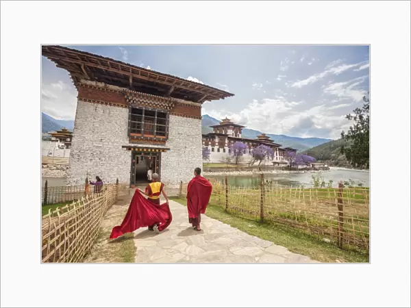 Two monks dressed in traditional red access the Punakha Dzong a former monastery