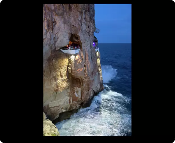 Bar built in cliff caves, Cova d en Xoroi in evening, Cala en Porter, Menorca, Balearic Islands