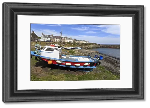 Boats on harbour foreshore at low tide on a sunny summer day, Craster, Northumberland
