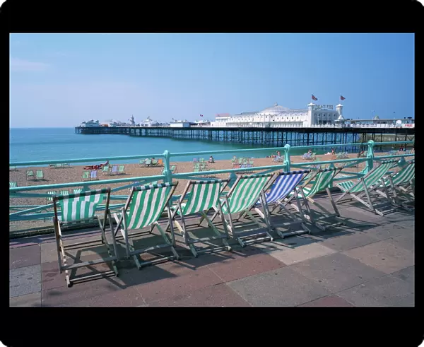 Deckchairs above the beach and the Palace Pier at Brighton, Sussex, England