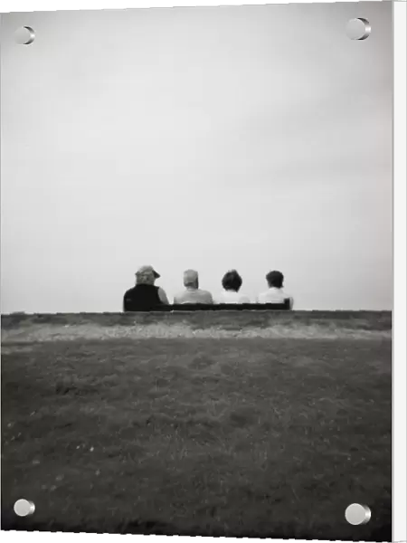 Image taken with a Holga medium format 120 film toy camera of four people on a bench overlooking the sea, Freshwater Bay, Isle of Wight, Hampshire, England, United