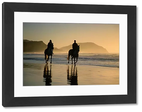 Horse riding on the beach at sunrise