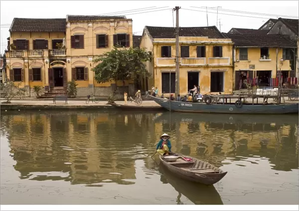 Boat on river in front of yellow coloured colonial buildings