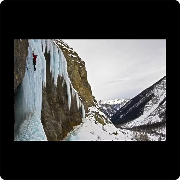 An ice climber ascending a frozen cascade in the Fournel Valley, Ecrins Massif, France