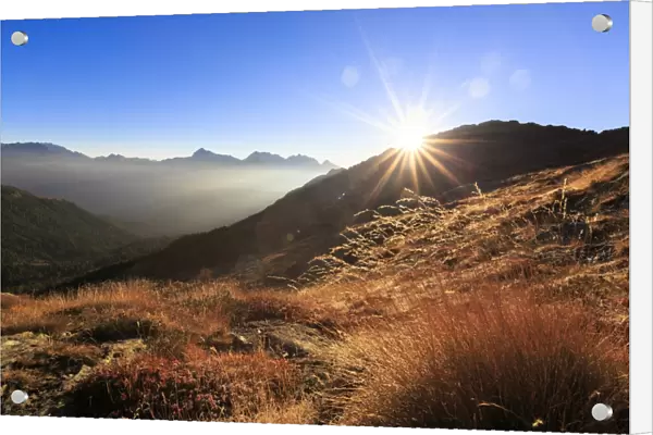 Sunbeams on alpine pastures with peak Scalino in the background, Val Torreggio, Malenco Valley