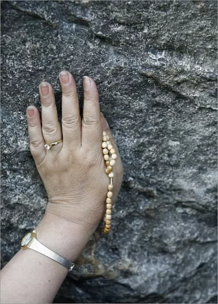 Pilgrim touching the Lourdes grotto, Lourdes, Hautes Pyrenees, France, Europe