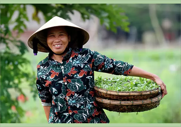 Smiling Vietnamese woman wearing the traditional palm leaf conical hat, Hoi An, Vietnam