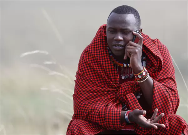 A Masai man talking on a mobile phone in the African savanna, Masai Mara Game Reserve