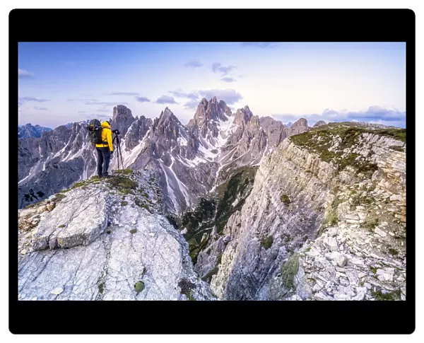 Man on top of rocks photographing Cadini di Misurina at sunrise, Dolomites