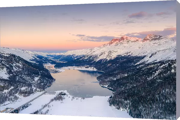 Aerial view of frozen Lake Silvaplana and Piz Corvatsch covered with snow at sunset