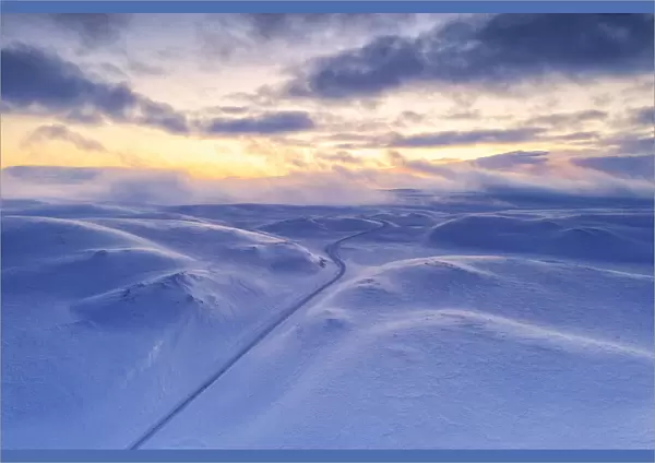 Arctic sunset over Tanafjordveien empty road crossing the snowy mountains after blizzard