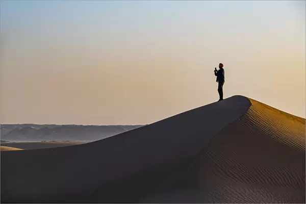 Man hiking through the sand dunes, Dirkou, Djado Plateau, Sahara, Niger, Africa