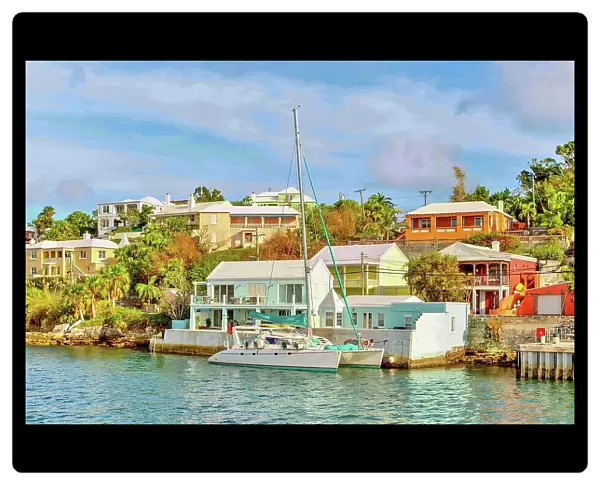 Catamaran in The Great Sound, moored in front of typical pastel coloured properties, Bermuda, Atlantic, North America