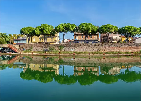 View of buildings and pine trees reflecting on the Rimini Canal, Rimini, Emilia-Romagna, Italy, Europe