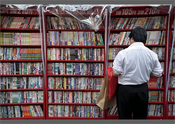 Man browsing Japanese manga comic books at a shop in Osaka, Japan, Asia