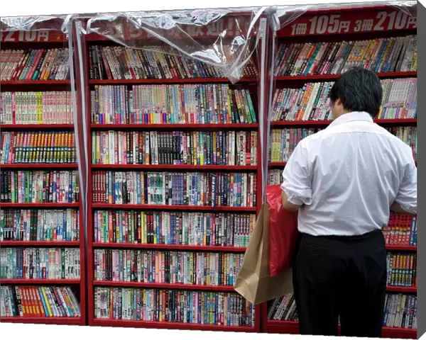Man browsing Japanese manga comic books at a shop in Osaka, Japan, Asia