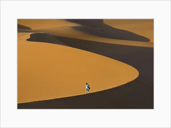 Tourist walking along a giant sand dune, Merzouga, Morocco, North Africa, Africa