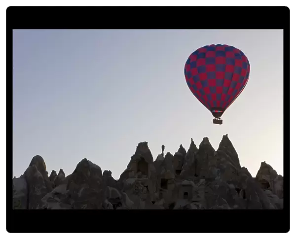 Hot air balloon taking off with tourists on board for a flight over the famous volcanic tufa rock formations around Goreme, Cappadocia, Anatolia, Turkey, Asia