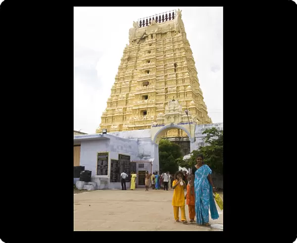 An Indian family walks in front of the gopuram of the Ekambereshwara Temple in Kanchipuram