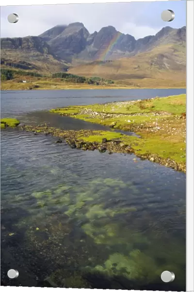 View across the clear waters of Loch Slapin to rainbow over the Cuillin Hills