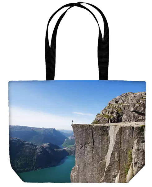 Man standing on Preikestolen (Pulpit Rock) above fjord, Lysefjord, Norway