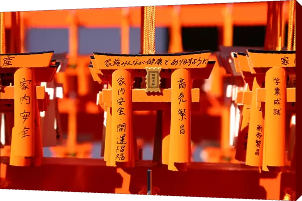 Miniature red torii gates with prayers at Fushimi Inari Shinto shrine in Kyoto, Japan