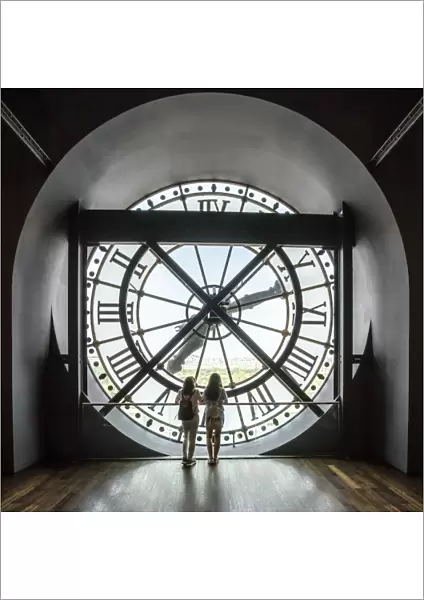 Two girls looking through a giant clock in Musee d Orsay, Paris, France