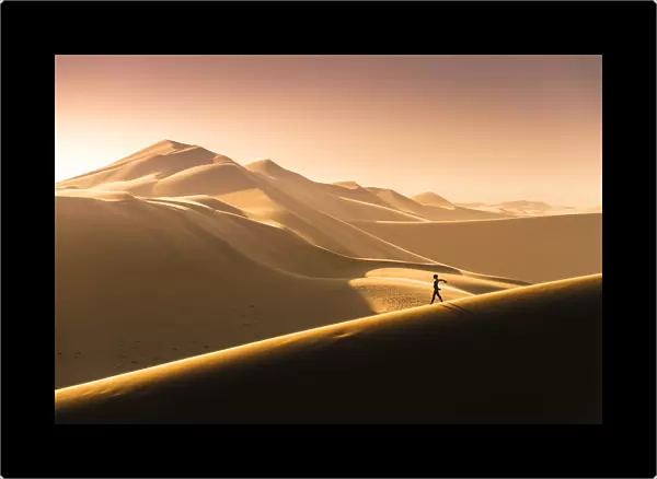 Walvis Bay, Namibia, Africa. Tourist walking on the sand dunes at sunset