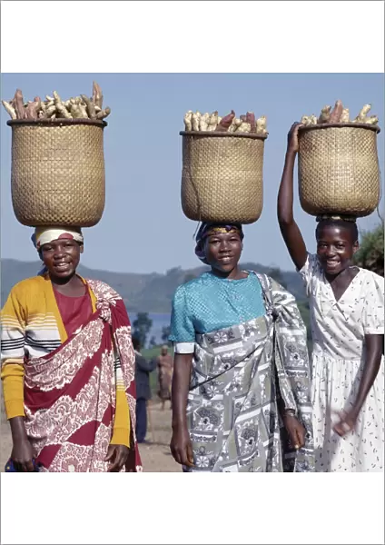 A group of cheerful women carry sweet potatoes to market