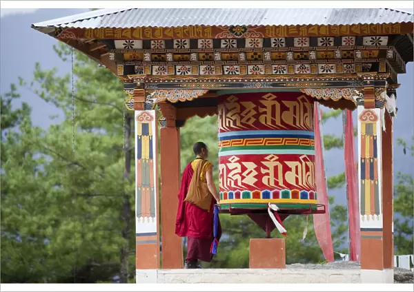 A monk and a prayer wheel on the path to the Paro Taktsang monastary in the Himalayan