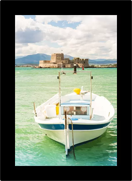 Close up of a boat docked in the Nafplio harbour and Bourtzi fortress in the background