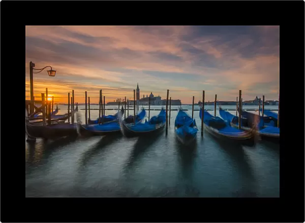 Moored gondolas at sunrise with San Giorgio Maggiore island in the background, Venice