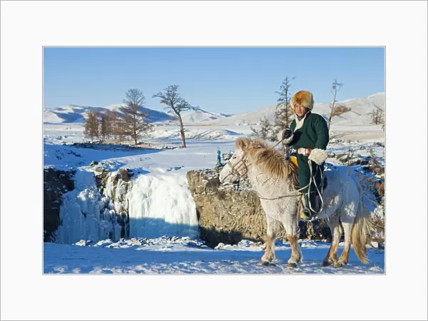 Mongolia, Ovorkhangai, Orkkhon Valley. A man sits on horseback by a frozen waterfall