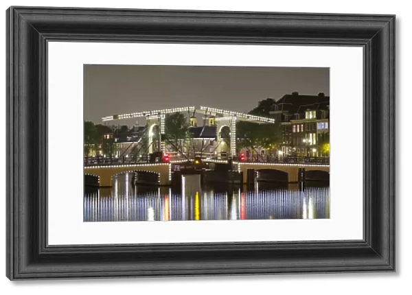 Magere Brug over the river Amstel illuminated at night, Amsterdam, North Holland
