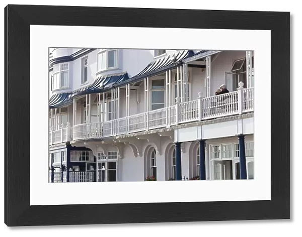 Retired couple sat on balcony, Regency houses, Sidmouth, Devon, UK