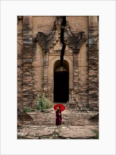 Novice monk standing in front of the unfinished Pahtodawgyi pagoda known for a crack