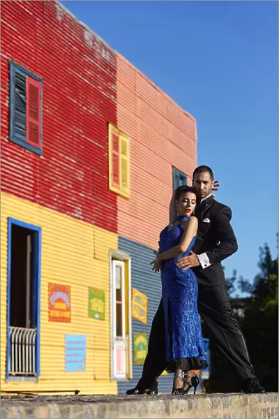 A couple of Professional Tango dancers with a colorful house of La Boca neighborhood in the background, Buenos Aires, Argentina. (MR)